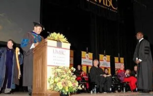 A man in graduation cap and gown standing at the podium.