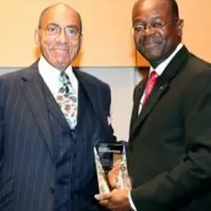 Two men in suits and ties holding a plaque.