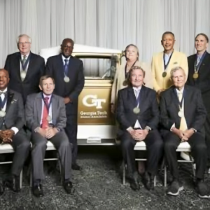 A group of men and women sitting in front of a truck.