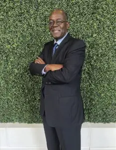 A man in suit and tie standing with his arms crossed.